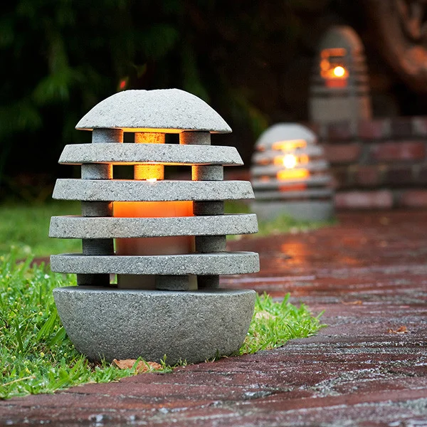 A stone lantern with a warm glowing light along a brick pathway in a garden.
