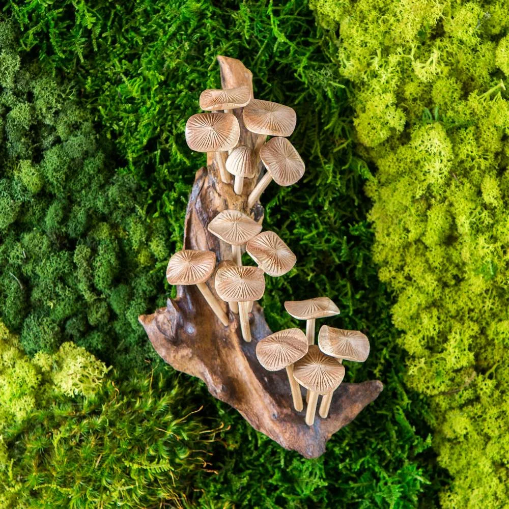 A wooden mushroom sculpture displayed against a lush green moss background.